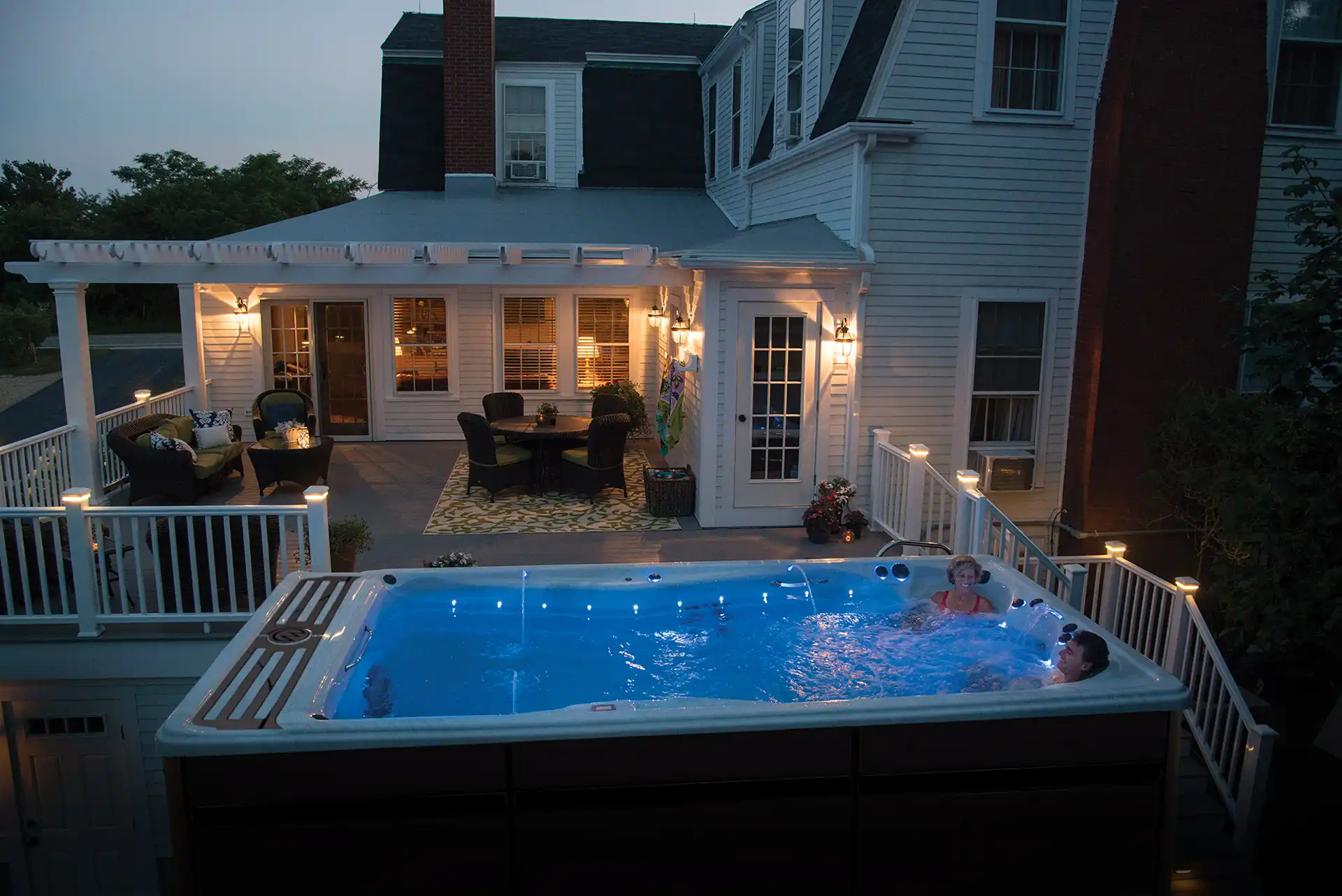 luxury swim spa at dusk with illuminated water features on long island