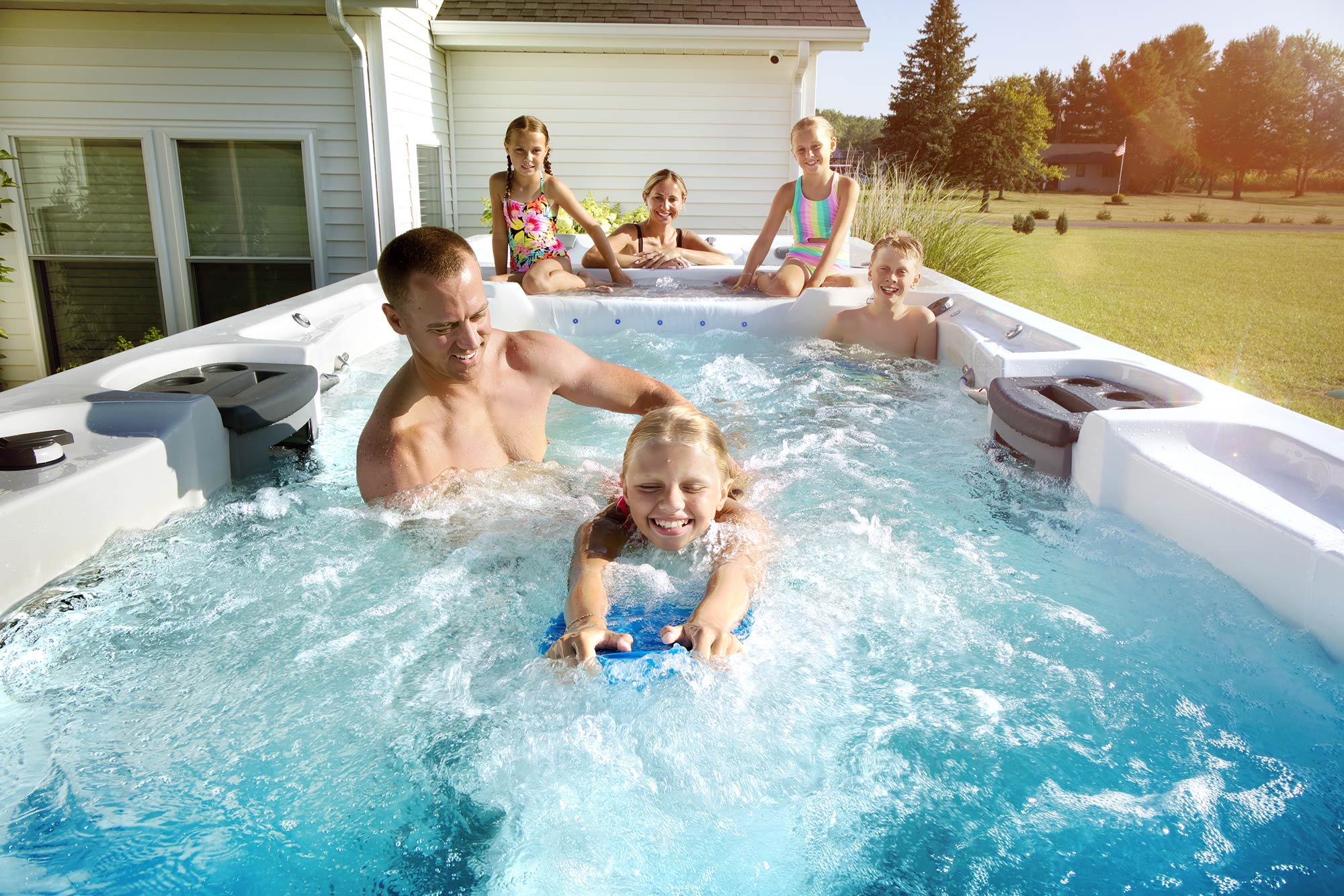 family enjoying swim spa with dual zones for swimming and hydrotherapy in backyard